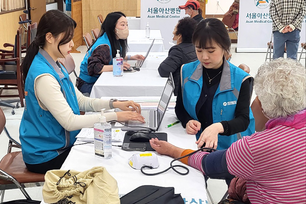 의료봉사에 참여한 직원이 환자 혈압을 측정하고 있다. 이미지